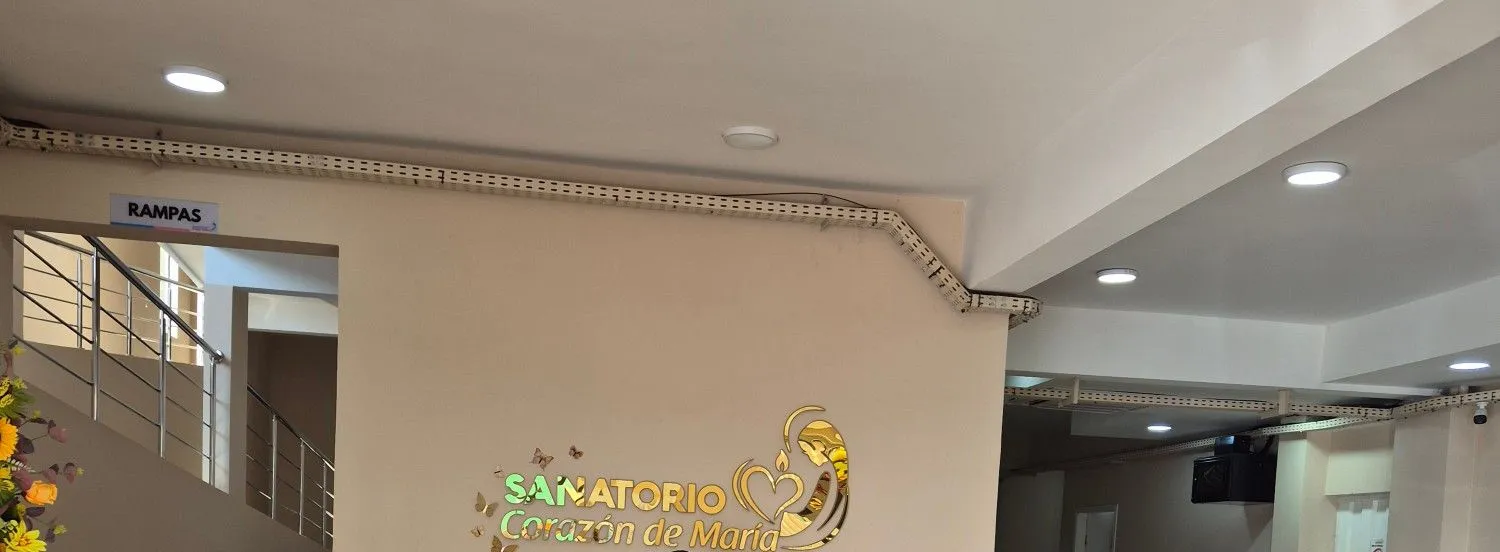 Recepción del sanatorio, con el logo dorado en la pared y la escalera con rampas